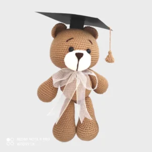 A close-up of a luxurious crocheted bear wearing a graduation cap, made with fine craftsmanship and attention to detail.