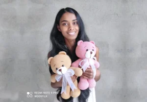 A young girl holding two crocheted teddy bears in her hands with a smile on her face.