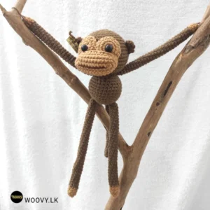 Adorable crocheted monkey with floppy ears and a playful smile.