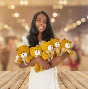 Smiling woman holding golden yellow handmade crochet teddy bears – amigurumi plush toys from Sri Lanka